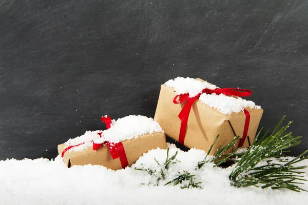 Vánoční dárky ve sněhu před tabulí — Stock fotografie