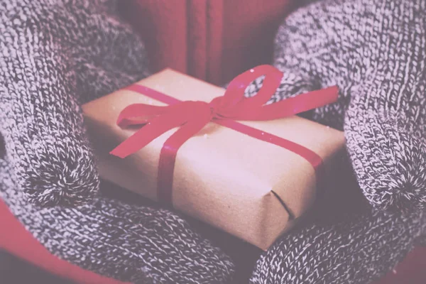 Manos abiertas sosteniendo un regalo envuelto con una cinta roja Vintage R — Foto de Stock