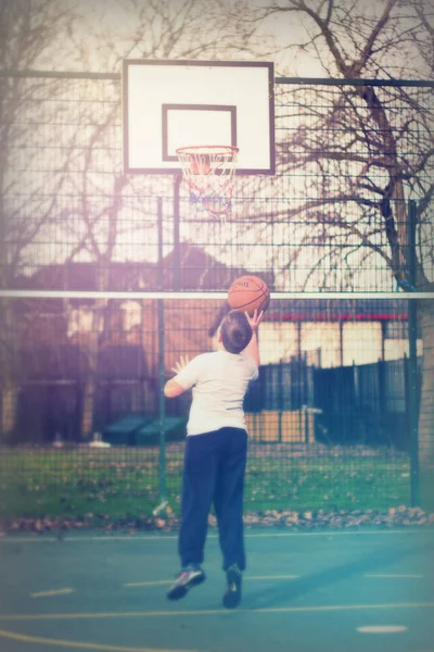 Дети играют в баскетбол в местном парке — стоковое фото