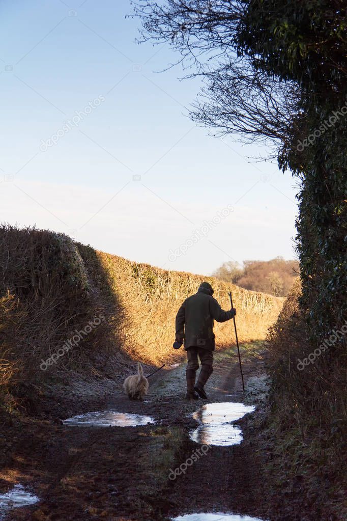 Man walking his dog along muddy country path