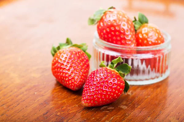 Fresas rojas brillantes sobre un fondo rústico — Foto de Stock