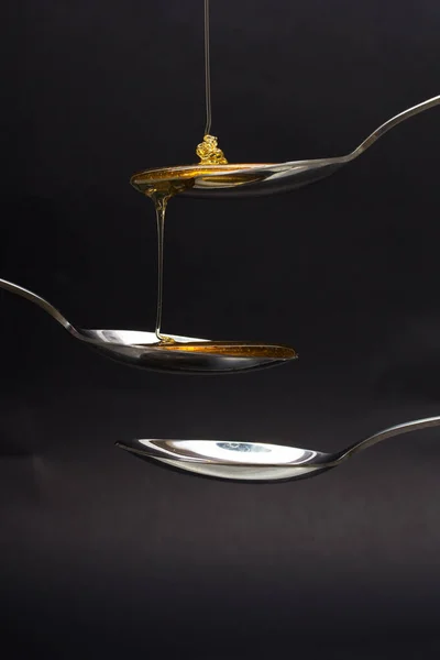 暗い背景に対してスプーンから注ぐ蜂蜜 — ストック写真