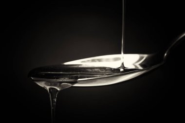 Tatlım kaşık karanlık bir arka plan karşı dökme