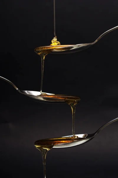 Honung hälla från sked mot en mörk bakgrund — Stockfoto
