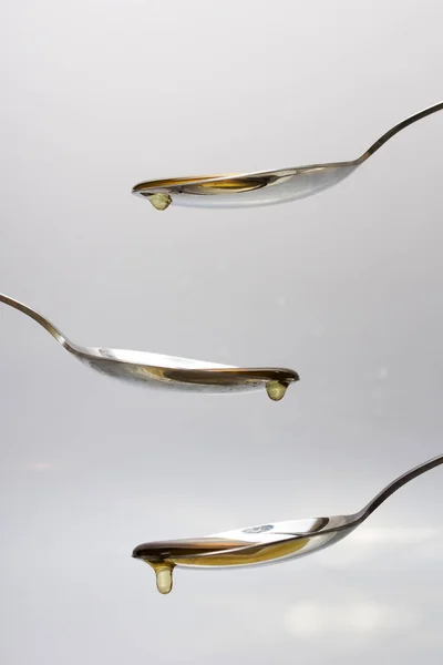 Miele versando da cucchiaio su uno sfondo leggero — Foto Stock