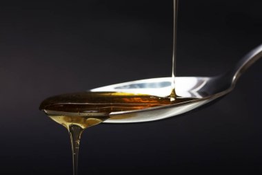 Tatlım kaşık karanlık bir arka plan karşı dökme