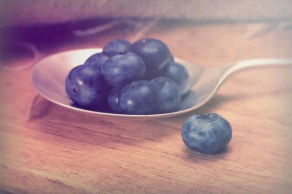 Blaubeeren und Löffel auf rustikalem Hintergrund — Stockfoto