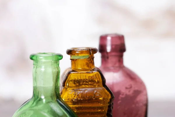 Farbige Glasflaschen auf rustikalem Hintergrund lizenzfreie Stockbilder