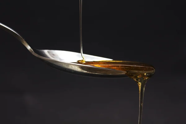 Honung hälla från sked mot en mörk bakgrund — Stockfoto