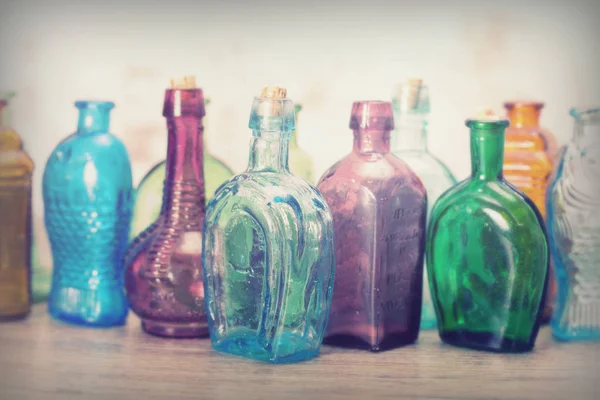 Цветные стеклянные бутылки на деревенском фоне — стоковое фото