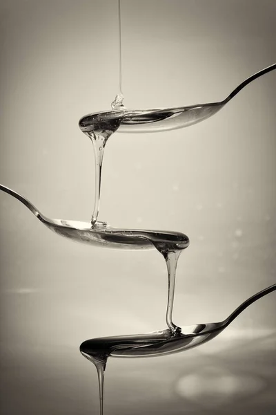 Miele versando da cucchiaio su uno sfondo leggero — Foto Stock
