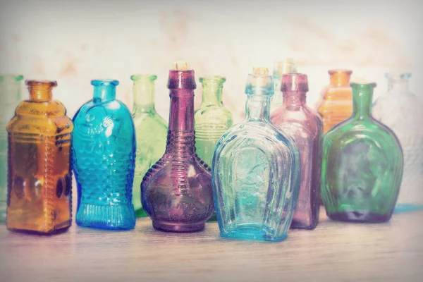 Bottiglie di vetro colorato su sfondo rustico Immagine Stock