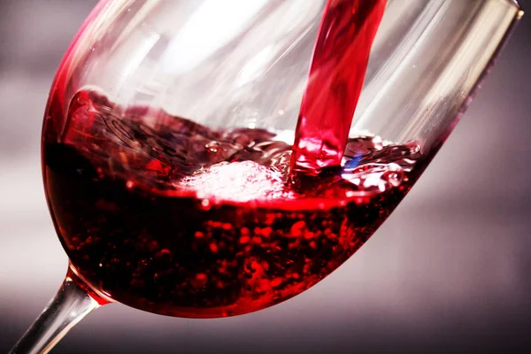 Glass of full bodied red wine being poured — Stock Photo, Image