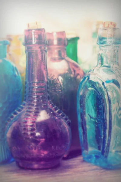 Bottiglie di vetro colorato su sfondo rustico — Foto Stock