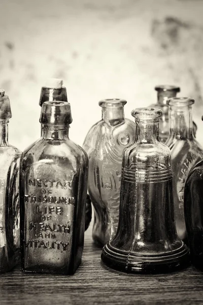 Bottiglie di vetro colorato su sfondo rustico Foto Stock