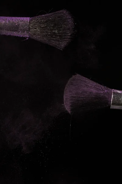 Макіяж пензлем з фіолетовим пилом на чорному тлі — стокове фото
