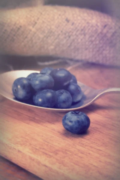 Blaubeeren und Löffel auf rustikalem Hintergrund — Stockfoto