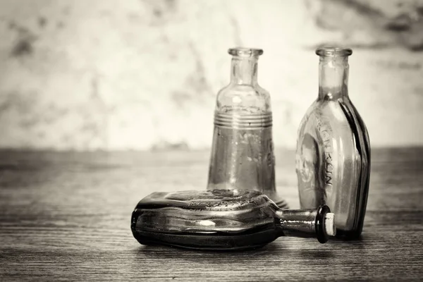 Botellas de vidrio de colores sobre un fondo rústico — Foto de Stock