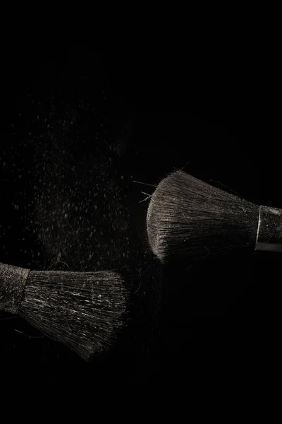 Макияж кисть с фиолетовой пыли на черном фоне — стоковое фото