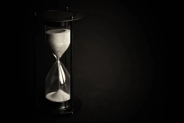 Large black hourglass against a black background — Stock Photo, Image