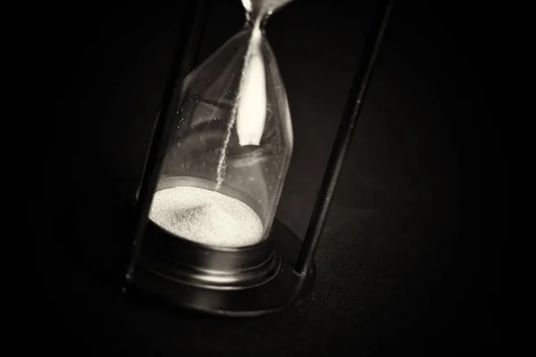 Large black hourglass against a black background — Stock Photo, Image