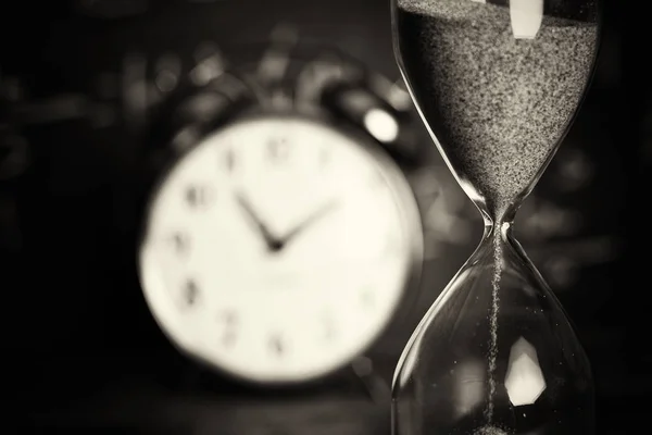 Hourglass on wood with a blackboard background — Stock Photo, Image