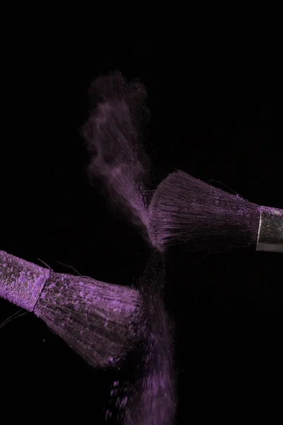 Макияж кисть с фиолетовой пыли на черном фоне — стоковое фото