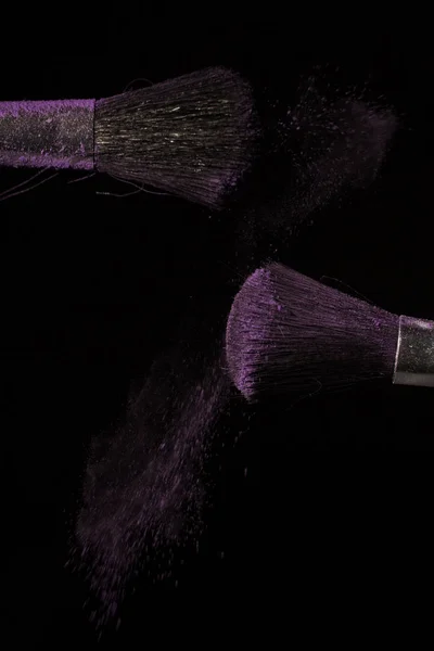 黒の背景に紫のほこりをブラシを作る — ストック写真
