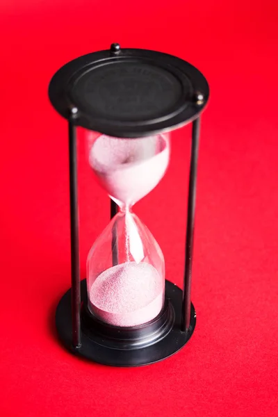 Large black hourglass against a red background — Stock Photo, Image