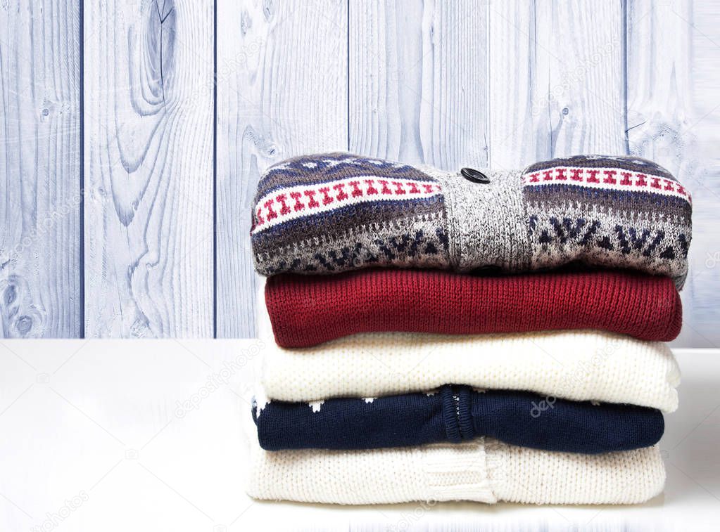A stack of sweaters on the wooden background.