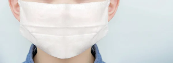 Young boy in medical face protection mask indoors on blue background