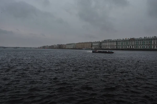 Tekne köprünün arka planına ve St. Petersburg 'un güzel binalarına karşı nehirde yüzer.