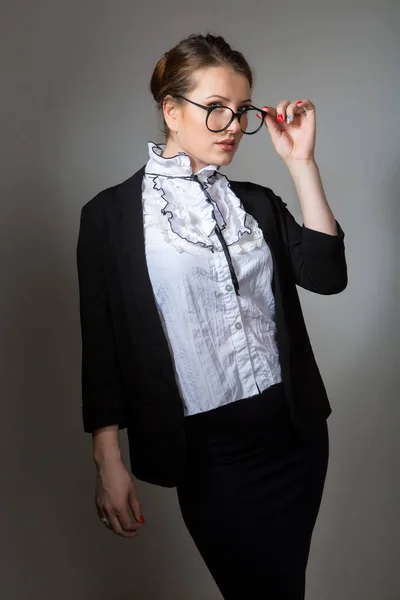 Portrait of an elegant businesswoman holding glasses against grey background. — Stock Photo, Image