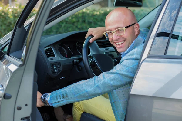 Hombre guapo sonrisa en la cara cerrando la puerta de su coche, las manos en whe — Foto de Stock