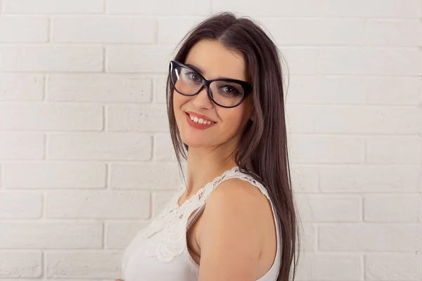 Feliz joven mujer con gafas sonriente aislado blanco ladrillos fondo pared — Foto de Stock