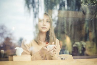 Arka planda açık bir yağmurlu bir gün yansıması ile düşünme bir aradan sonra yalnız bir barda yalnız hüzünlü kadın