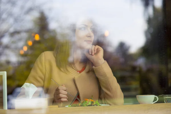 Красивая молодая женщина с чашкой кофе глядя в кафе — стоковое фото