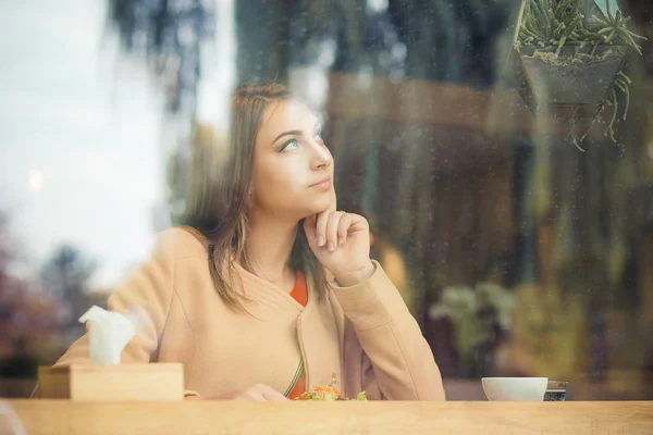 Hermosa mujer joven con taza de café mirando hacia otro lado en la cafetería — Foto de Stock
