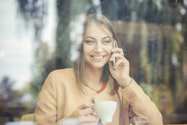 Empresaria bebiendo café / té y usando la computadora del teléfono en una cafetería —  Fotos de Stock