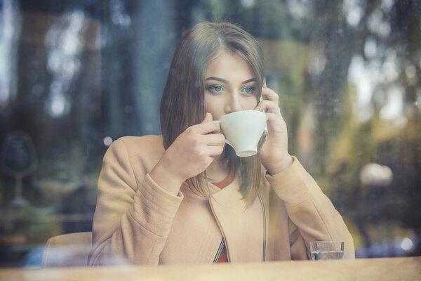 Charming woman with beautiful smile reading good news on mobile phone during rest in coffee shop, happy Caucasian female watching her photo on cell telephone while relaxing in cafe during free time 