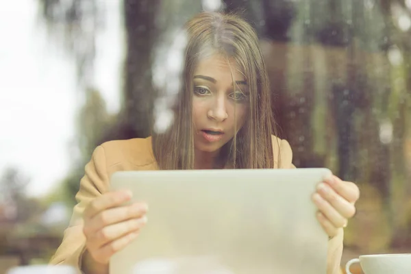 Mujer sorprendida sosteniendo la computadora, pantalla de la tableta del ordenador portátil que mira sorprendido en la cafetería — Foto de Stock
