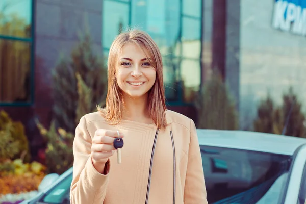 Щаслива, усміхнена, молода приваблива жінка, покупець біля своєї нової машини показує ключі — стокове фото