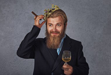 Bardak içecek ve puro ile yakışıklı adam kafasına altın taç düzenler 