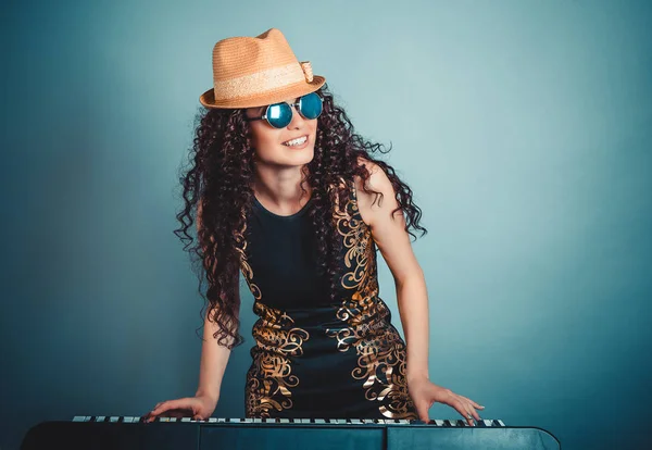 Rock pop star. Woman playing synthesizer isolated blue background