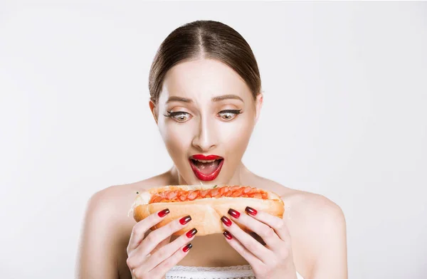Kırmızı dudaklar yaklaşık ısırmaya bir hamburger holding ile güzel komik kadın beyaz gri arka plan izole. Sağlıksız beslenme hayat kavramı — Stok fotoğraf