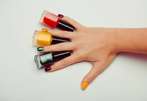 Bouteilles de vernis à ongles multicolores dans les mains — Photo