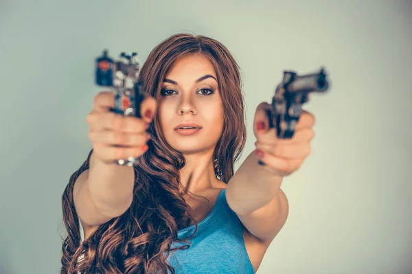 Schöne junge Frau, Mädchen mit Gewehren isoliert auf der grünen Wand. — Stockfoto