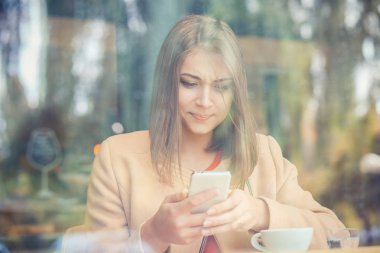 Cep telefonu izole kahvehane arka plan tutan kadın