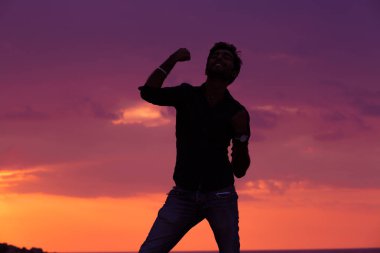 Başarılı adam silah yaz günbatımı üzerinde yükselterek. Başarı kutluyor kadar erkek silah.