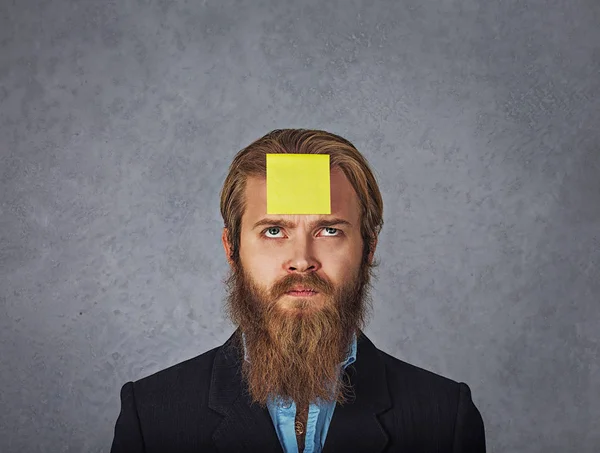 serious worried business man looking up to the sticker stick on forehead